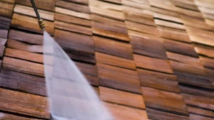 Close up of a pressure washing hose cleaning wooden shingles