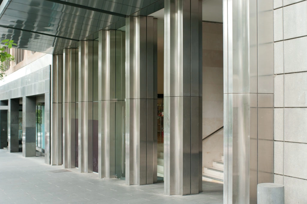 Columns in the front portico of a modern city buildng, clad with stainless steel